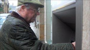 John Shepherd-Barron using cash dispenser at Barclays bank in Enfield, north London