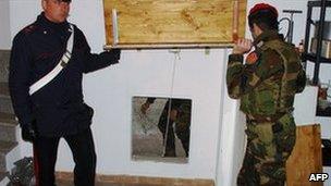 Italian policemen show the entrance to the bunker where a suspect was found, 8 March