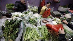 Vendors sell vegetables at a market in China