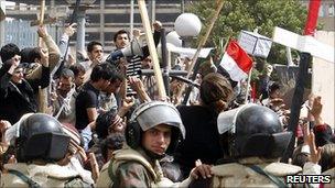 Christians protesting ringed by soldiers with riot gear.