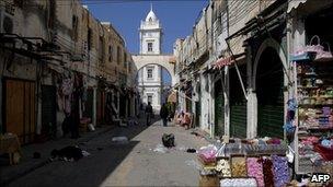 Libyan men walk past the lowered iron shutters of shops at the market of Tripoli, 9 March 2011