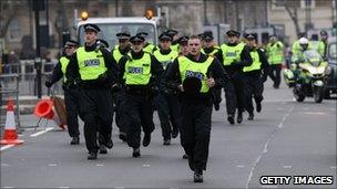 Riot police officers run along Whitehall as student demonstrators march to Parliament