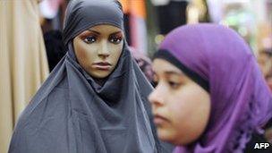 A woman in a headscarf passes a dummy covered with a veil at a stand during a meeting of French Muslims in Le Bourget, outside Paris, April 2010