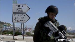 An Israeli soldier guards a road junction near Itamar in the West Bank - 12 March 2011