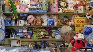 A vendor sits among mostly Chinese manufactured toys for sale in a shopping gallery known for selling cheap Asian products in Sao Paulo, 2 February 2011