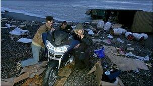People taking a motorbike off the beach