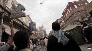 Anti-government protestors react as a military helocopter flies overhead during clashes in Sanaa, March 18, 2011