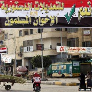 Egyptians in Cairo walk under a banner by Egypt's Muslim Brotherhood calling for a "Yes" vote.