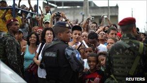 People wait to catch a glimpse of Barack Obama in Cidade de Deus