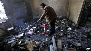 A Syrian man damps down with a fire extinguisher a burned court room in the southern city of Deraa.