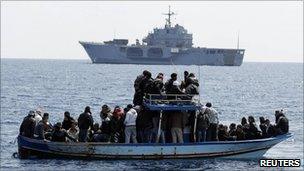 Migrants from Tunisia on a boat in front of Italian navy ship San Marco (23 March 2011)