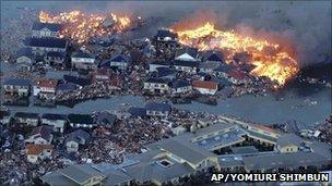 Flaming houses surrounded by debris and water following a tsunami, Natori city