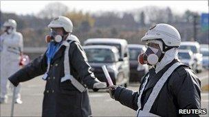 Police wearing respirators guide people away from the Daiichi nuclear plant on 12 March 2011