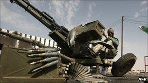 A Libyan rebel sits at an anti aircraft gun in the strategic oil town of Ajdabiya