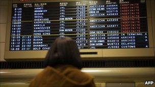 A woman watches a board at Narita airport in Tokyo