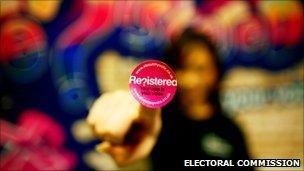 A woman with a sticker that says 'Registered?' on the end of her finger.