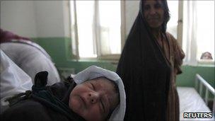 A midwife holds up a baby as the mother looks on at a hospital in the Afghan city of Farah in this August 10, 2009 file photo.