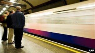 Commuters wait on a platform for a Piccadilly Line underground train