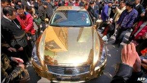 Crowd gathers to admire a gold-plated Infiniti luxury sports car in Beijing