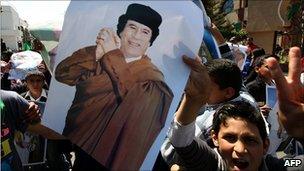 A boy holds a picture of Muammar Gaddafi at a protest outside the UN offices in Tripoli, 7 April 2011