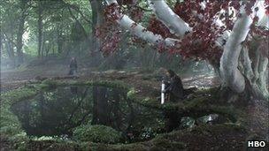 Sean Bean in armour kneeling at pond in forest