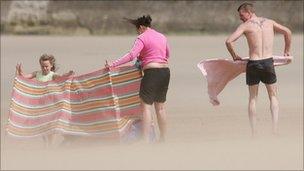 A family try to erect a wind-break on the beach