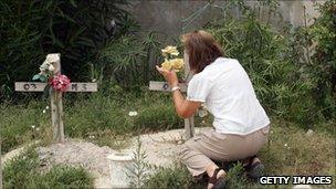 Woman lays flowers at makeshift tomb