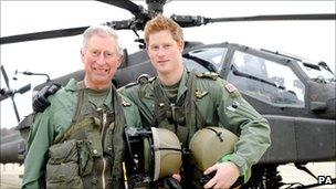 Prince Charles with his son Prince Harry standing in front of an Apache helicopter