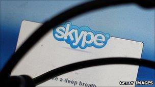 An image of a headset in front of a monitor displaying Skype software