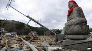 A statue of the guardian of children sits among the rubble at Ishinomaki