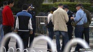 Plainclothes police watch as uniformed policemen question CNN reporter Stan Grant (C) and colleagues, Beijing April 24, 2011