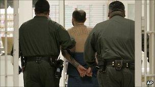 Inmate in a California prison being escorted by guards