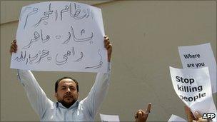 A Syrian carries a banner that reads: "Criminal regime, Bashar, Maher, Rami and Hezbollah" during a demonstration outside the Syrian consulate in Dubai (24 March 2011)