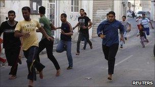 Bahraini men flee during a protest as riot police enter their village of Dai, east of Manama, on 24 March