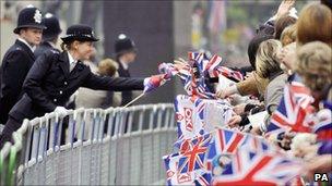 A police officer passes a flag to a member of the public