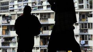 Workers silhouetted against a public housing estate in Hong Kong