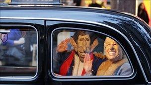 A man and woman dressed as Prince Charles and Queen Elizabeth II wave from inside an English cab in Sydney