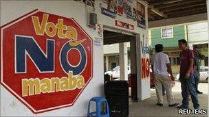 People walk past a painted No sign in Chone