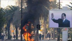 Smoke rises from fire left after clashes between security forces and demonstrators in Tunis on 14 January 2011 after Tunisian President Zine al-Abidine Ben Ali's resignation