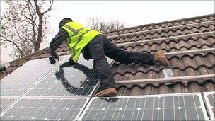 Solar panel installer drilling panels to a roof