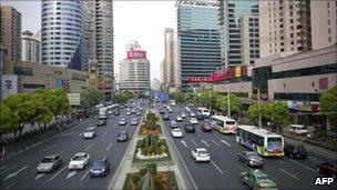 Cars drive past high rise buildings in a business district of Shanghai