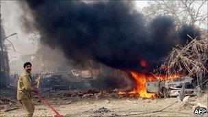 A Pakistani firefighter shouting in front of burning vehicle used by a suicide bomber