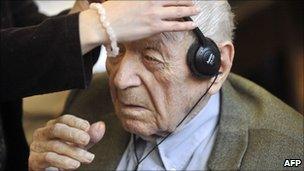 An official helps Sandor Kepiro with headphones at court in Budapest, Hungary (10 May 2011)