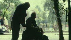 Carer pushing man in wheelchair