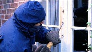 Posed image of burglar breaking into a house