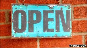 Open sign hanging on brick wall