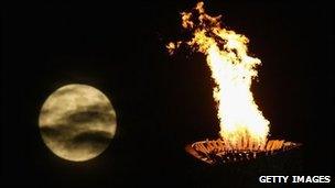 The moon rises over the Olympic torch and flame and the National Stadium during the Beijing 2008 Games