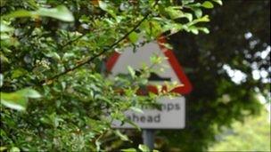 Guernsey road signs slightly obscured by vegetation