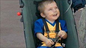 Harrison Stedman at 20 months old, receiving oxygen from a cylinder under the buggy.