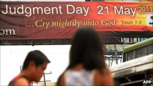 Pedestrians walk past a banner with a message that reads "Judgement Day May 21, 2011" at a street in Manila on 21 May, 2011